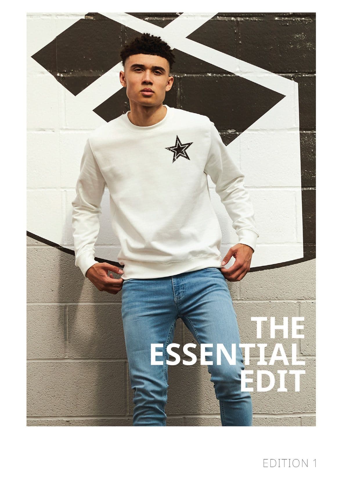 Front cover of The Essential Edit, Edition 1: a model in a white sweatshirt against a painted brick wall